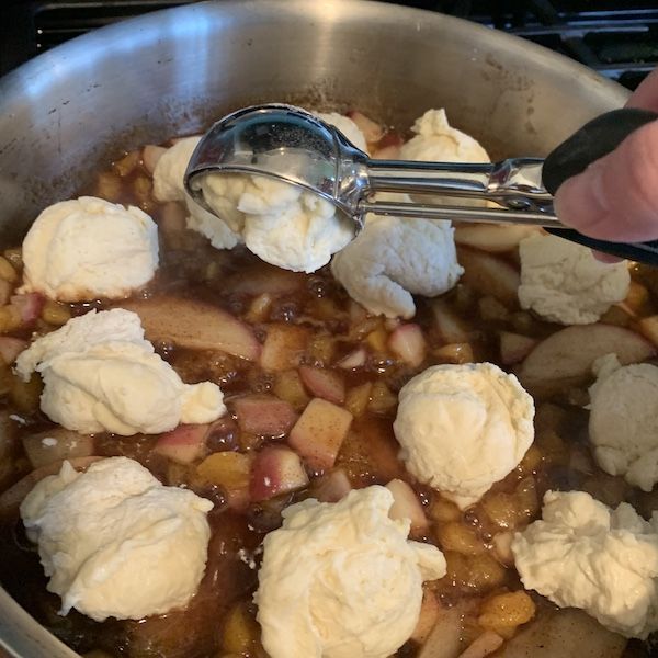 a person is stirring some food in a pot with ice cream on the top and toppings