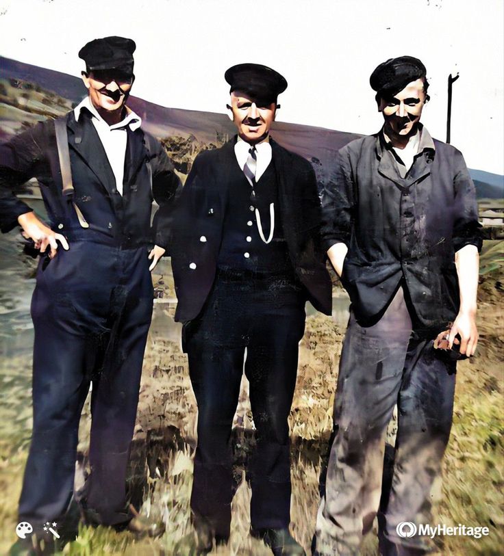 three men standing next to each other in the grass