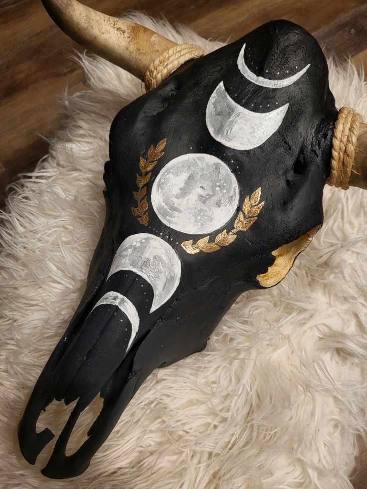 an animal's skull with horns and moon phases painted on it, sitting on a white rug