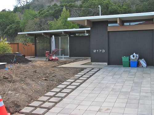 a house that is in the middle of some dirt and has a large yard area next to it