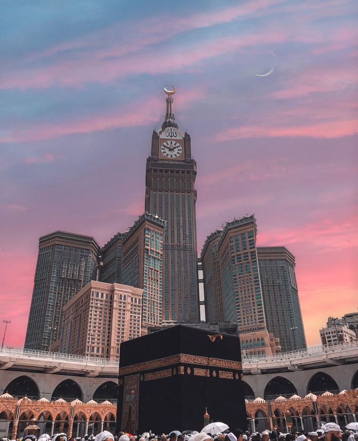 the ka'bah is located in front of some tall buildings with a clock tower