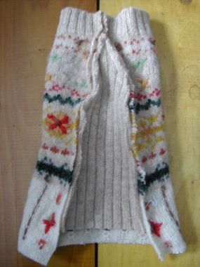 a pair of white knitted mittens sitting on top of a wooden floor next to a wall