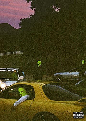 two people in green alien heads are seen through the window of a yellow sports car