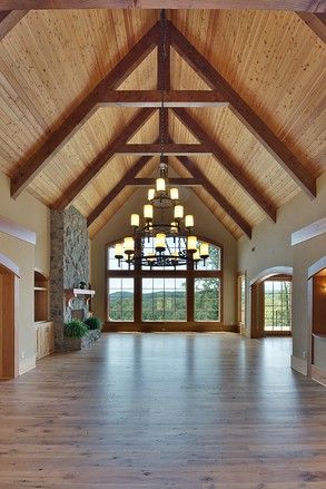 a large open room with wood floors and vaulted ceiling, lights on either side of the windows