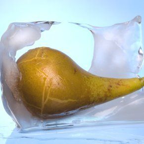 a pear in an ice cube with water splashing on it's side and inside