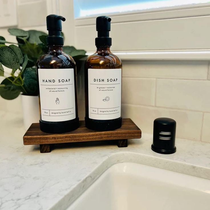 two bottles of hand soap sitting on top of a counter