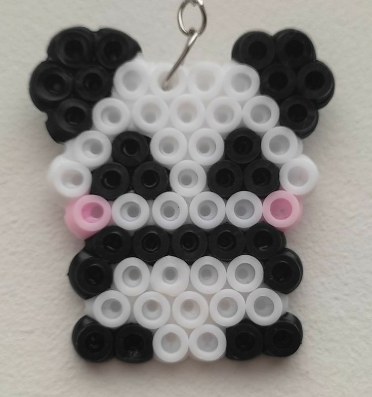 a black and white panda bear with pink eyes is hanging from a silver metal hook