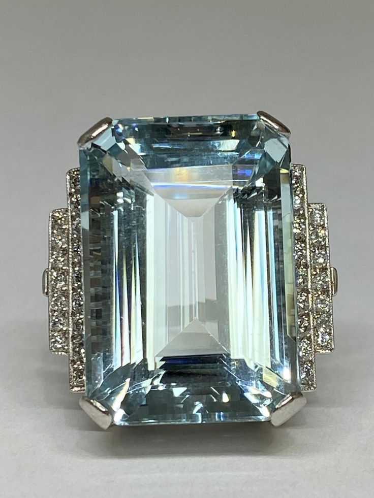 Take a dive into this spectacular crystalline blue aquamarine adorning your finger! Weighing in at show stopping 38.72carats, the elegantly proportioned emerald-cut aquamarine glistens, gleams, and glows in high profile. Accented at the shoulder with millgrain bezel set sparkling round brilliant cut diamonds. Superbly hand crafted in platinum this ring would make an excellent addition to any jewelry collection. Aquamarine weight 38.72ct, The aquamarine measures 25.90mm length, 17.60mm width and Blue Emerald, Platinum Diamond Rings, Aquamarine Engagement Ring, Contemporary Ring, Aqua Marine, Platinum Ring, Aquamarine Blue, Round Brilliant Cut Diamond, Bezel Setting