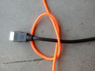 an orange and black cord connected to a computer mouse on the ground with wires attached