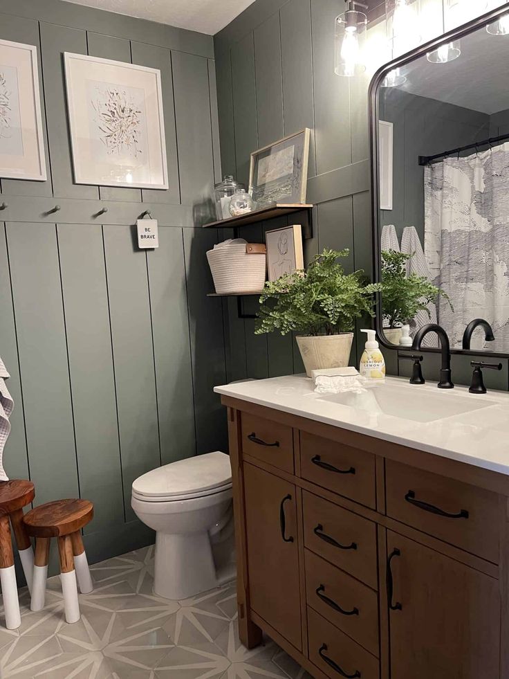 a white toilet sitting under a bathroom mirror next to a wooden sink vanity with two stools