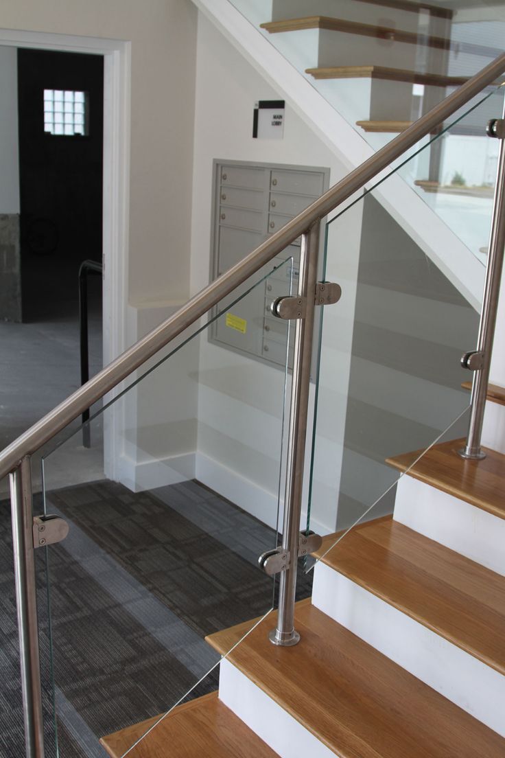 a stair case with glass railing and wood handrails in an empty room next to a door