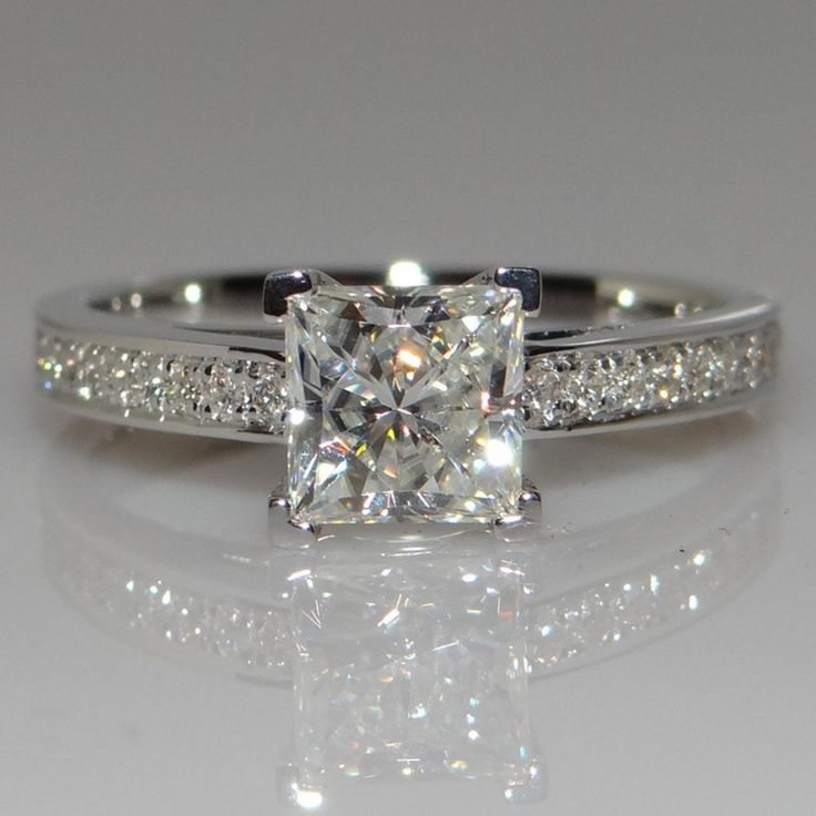 an engagement ring with a princess cut diamond and pave set diamonds on the sides