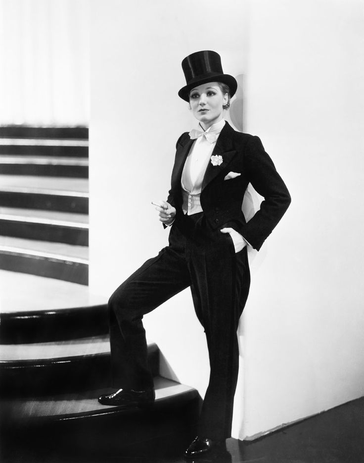 a man in a suit and top hat poses for a photo with his hands on his hips