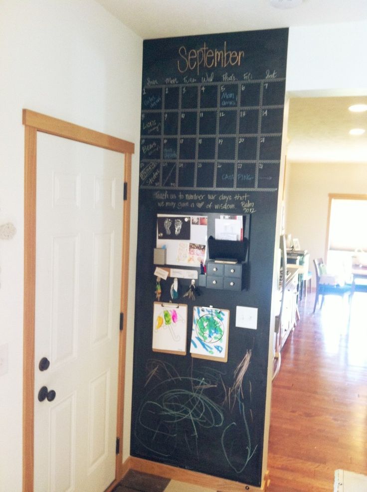 a blackboard with writing on it in a room next to a door and table