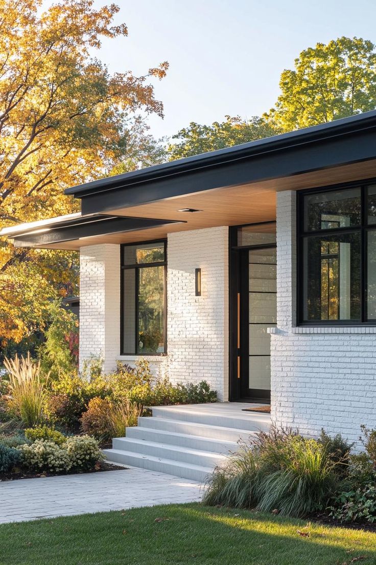 a white brick house with black trim on the front door and steps leading up to it