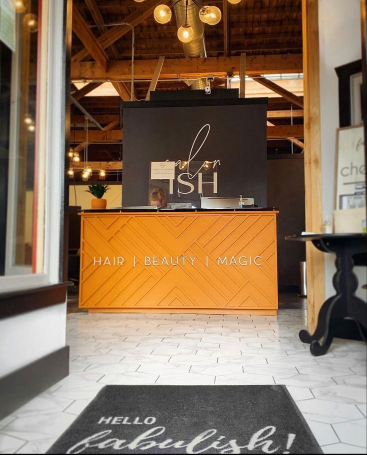 the front desk of a hair salon with lights hanging from it's ceiling and windows