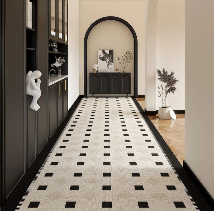 the hallway is decorated with black and white tile, along with an arched doorway that leads to another room