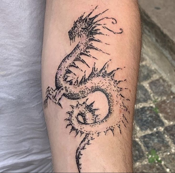 a man's arm with a dragon tattoo on the left side of his arm