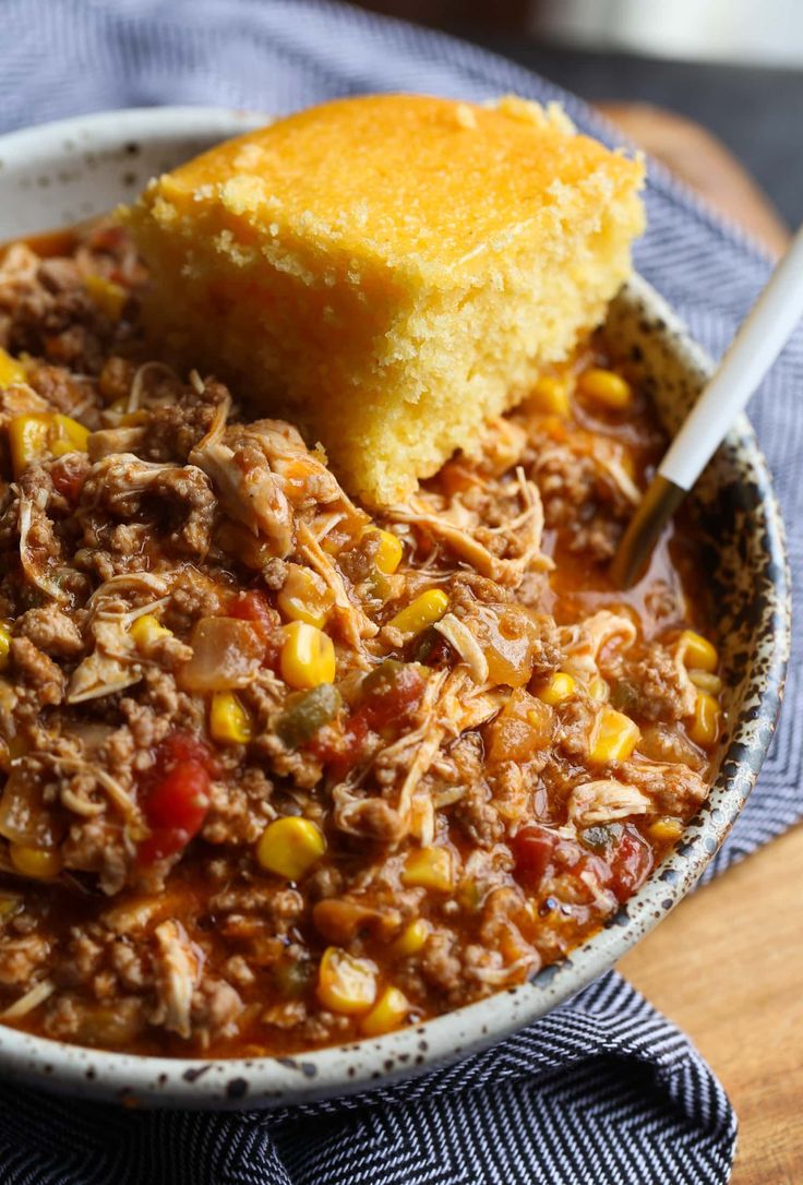 a bowl filled with chili and corn next to a piece of bread