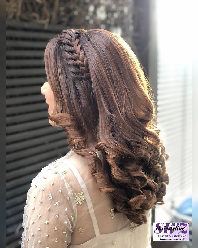 a woman with long hair wearing a white dress and braiding her hair into a half - up style