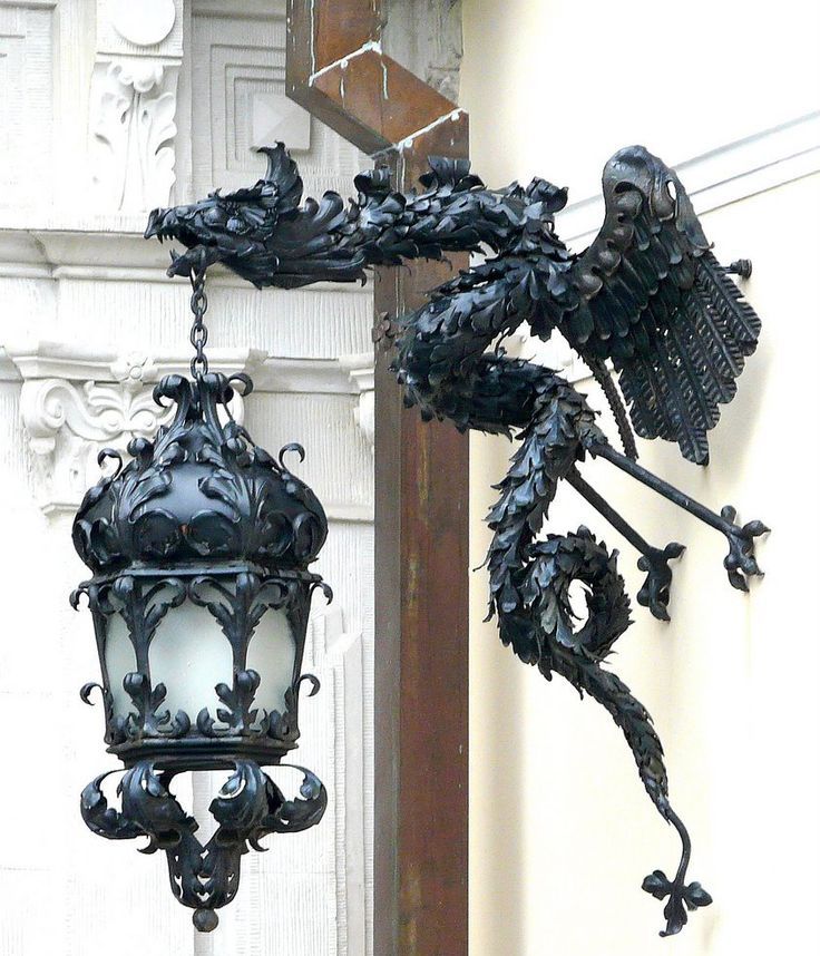 an ornate light fixture hanging from the side of a building with intricate carvings on it