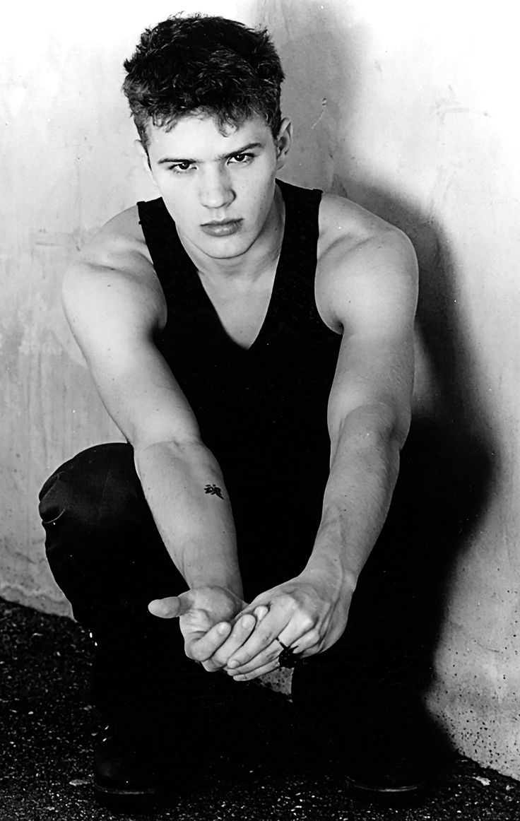 black and white photograph of a young man with his hands on the ground in front of him