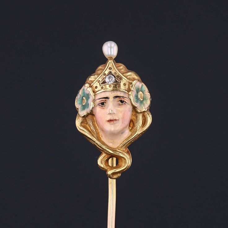 During the turn of the nineteenth century, artisans were inspired by the changing roles of women in society and began depicting the free flowing feminine form in brooches, bracelets, rings and more. This antique stickpin (circa 1890-1900) features a woman of 14k gold, adorned in enamel with a single diamond crown and a pearl accent.  The pin head measures 0.9 inches by 0.5 inches wide with the entire pin measuring 1.9 inches long. It is in very good condition; however there is a chip to the enam Yellow Gold Enamel Brooches, Art Deco Yellow Gold Collectible Brooches, Art Nouveau Enamel Brooch Jewelry, Victorian Brooches For Ceremonial Occasions, Gold Formal Enamel Pin, Gold Enamel Art Nouveau Brooches, Art Nouveau Yellow Gold Collectible Brooches, Victorian Style Enamel Pin Gift, Collectible Art Nouveau Hallmarked Brooch