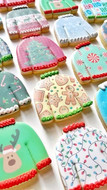 decorated cookies are arranged in rows on a white tablecloth with christmas sweaters and snowflakes