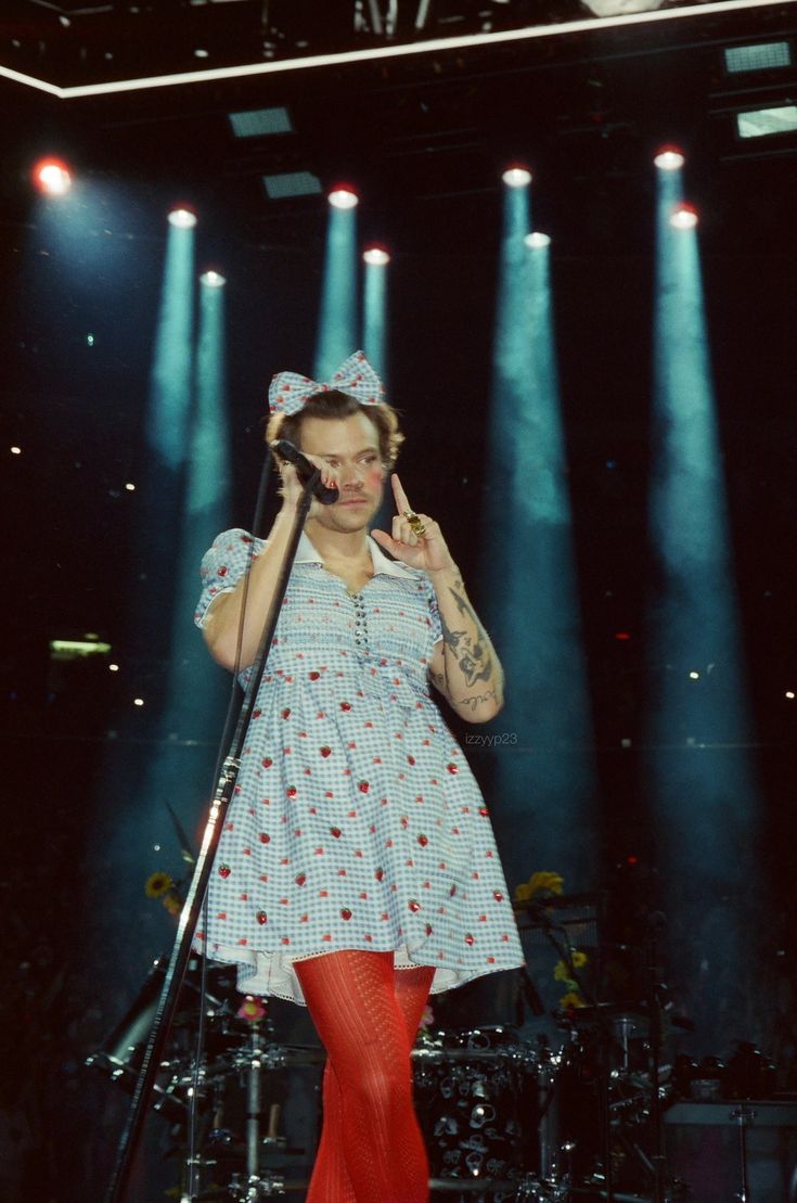 a woman standing on top of a stage while holding a cell phone to her ear