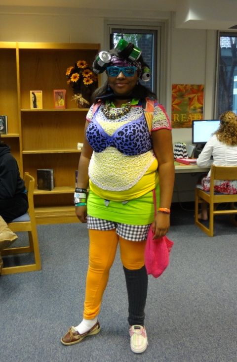 a woman in colorful clothing standing in front of a bookshelf filled with people