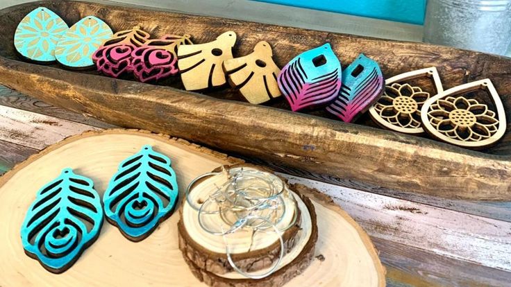 wooden earrings are sitting on a table next to a piece of driftwood and some other items