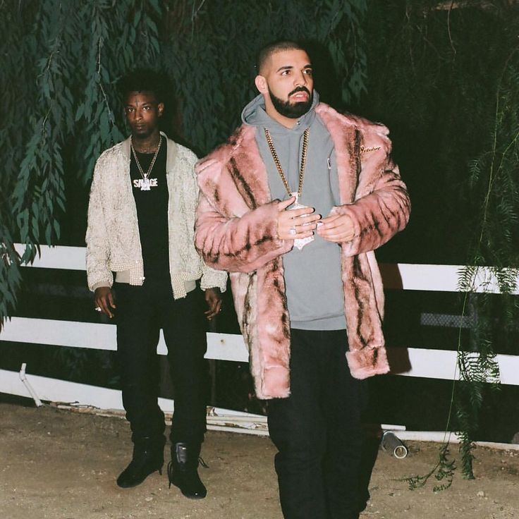 two men standing next to each other in front of a fence