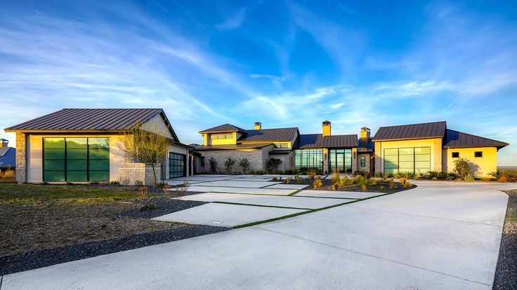 a large house sitting on the side of a road next to a lush green field