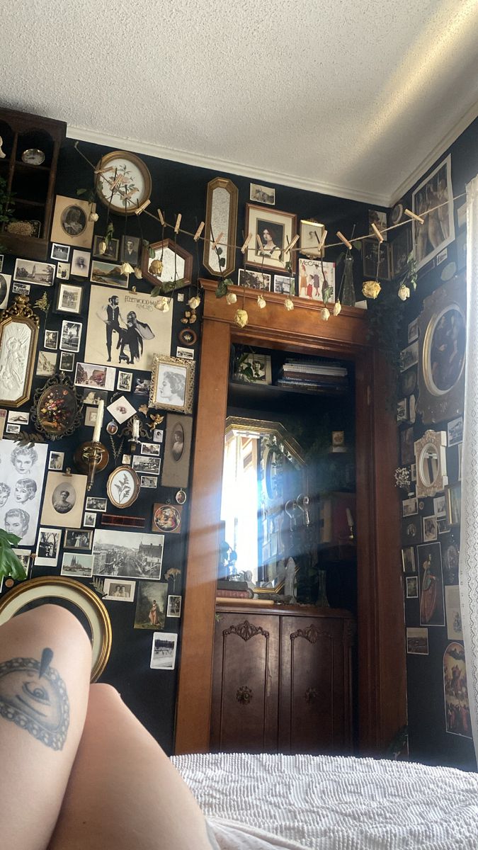 a woman's legs are shown in front of a wall with pictures and clocks on it