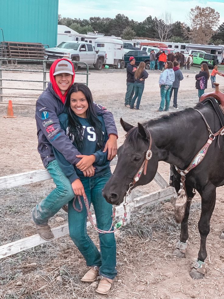 a man and woman standing next to a horse in an enclosure with other people around