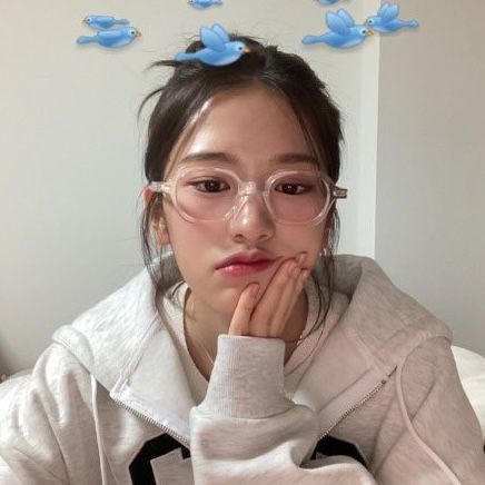 a young woman wearing glasses sitting in front of a laptop computer with blue birds above her head