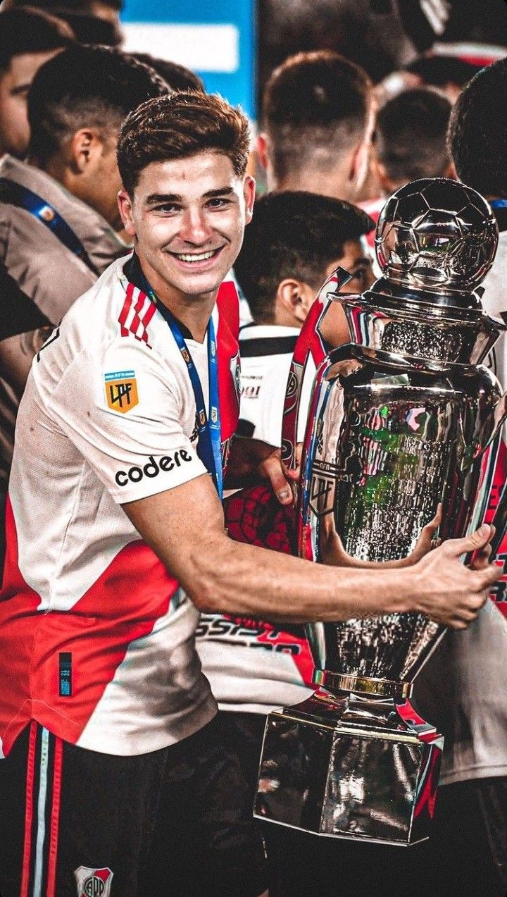 a young man holding up a trophy in front of other people at a soccer game