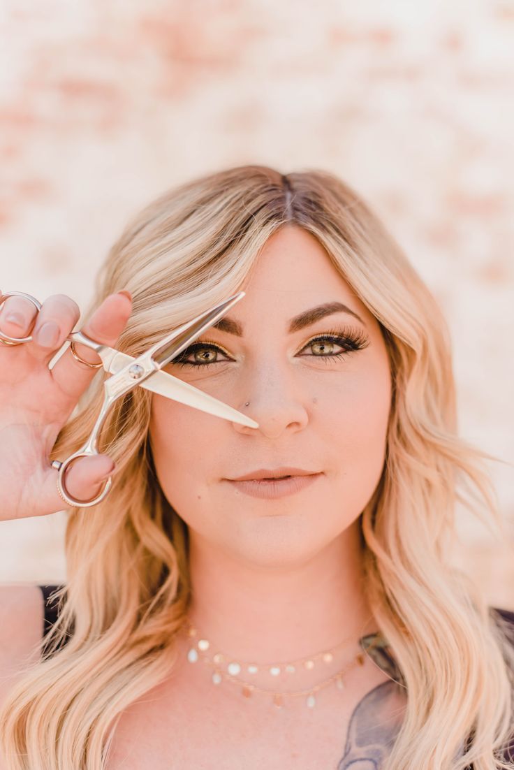 a woman is holding scissors over her eyes