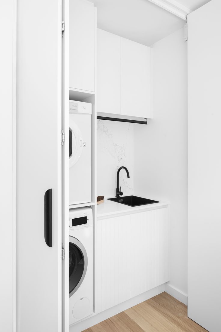 a washer and dryer in a small room with white cabinets on the wall