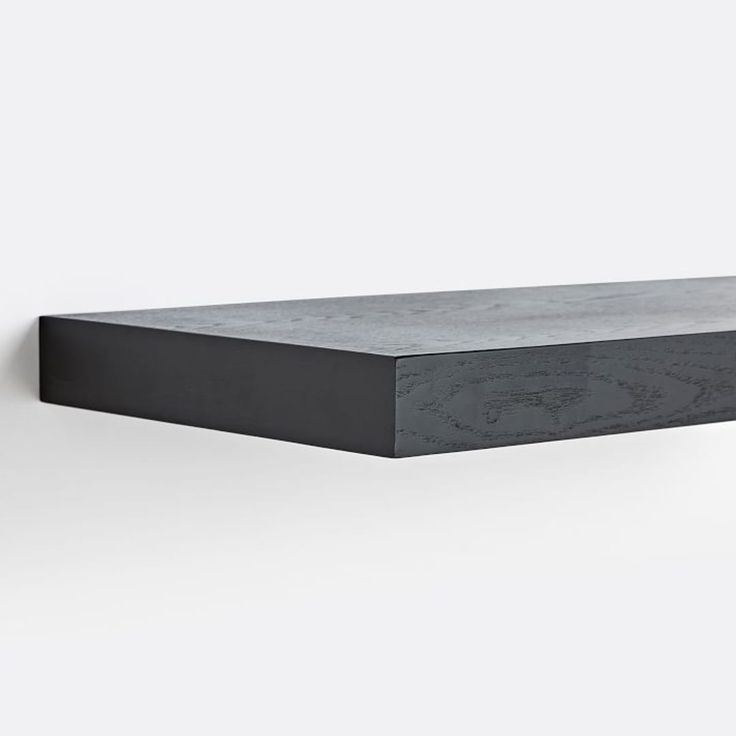 a black shelf on the wall with a white back ground and grey walls behind it