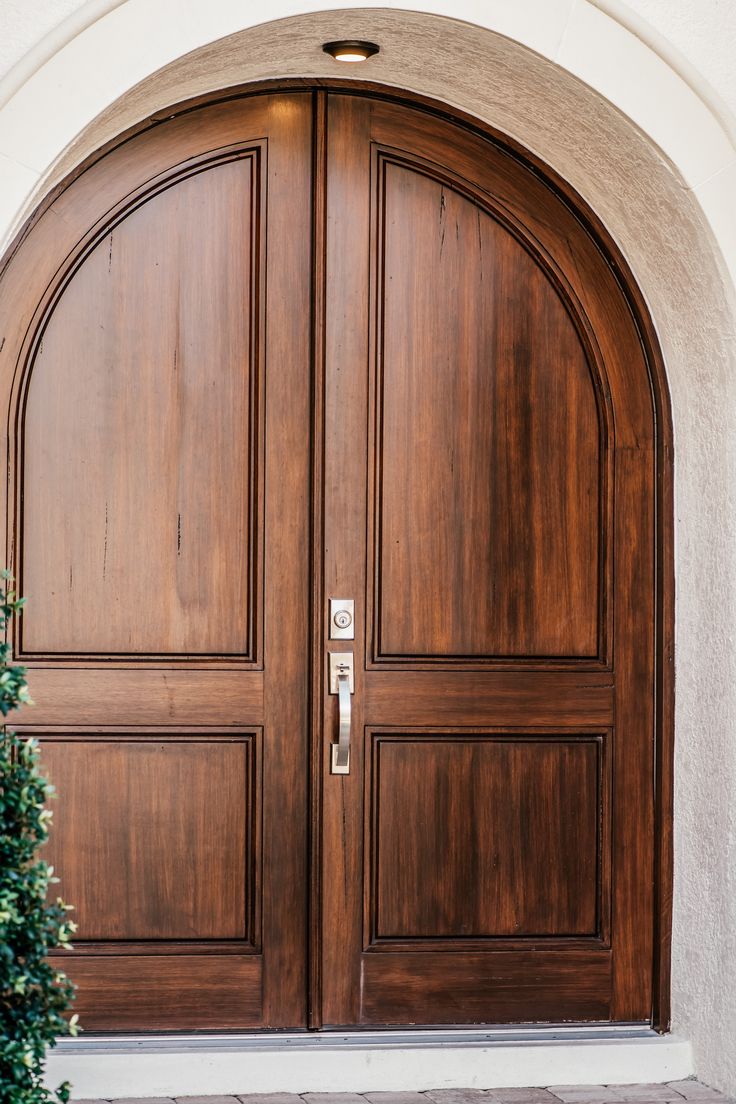 an arched wooden door with two sidelights