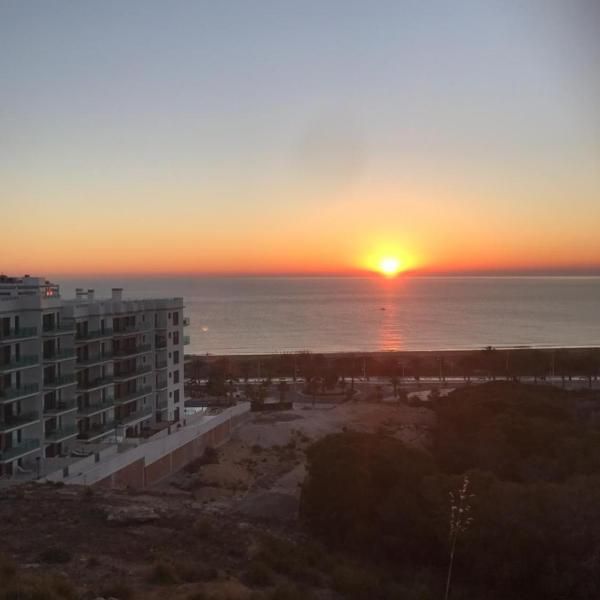 the sun is setting over the ocean and buildings