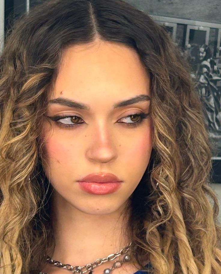 a close up of a person with long curly hair wearing a choker and necklace