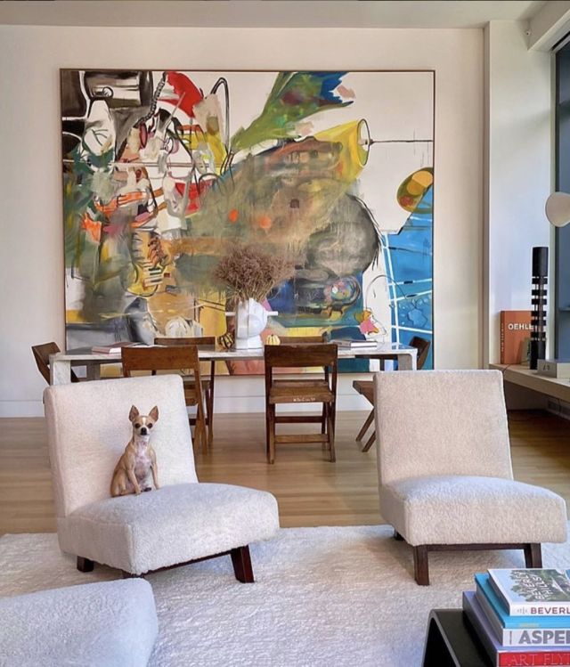 a living room with two chairs and a dog sitting on the floor in front of a painting