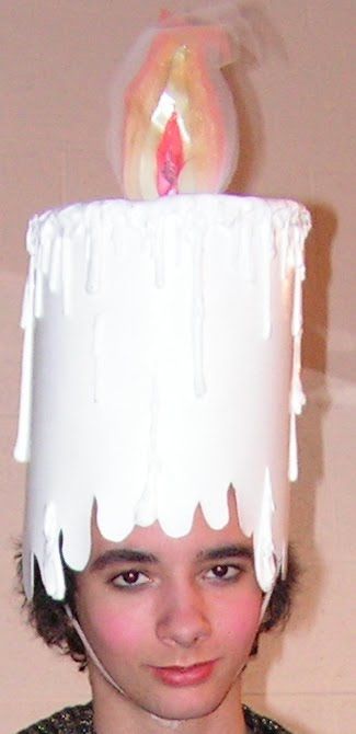 a girl wearing a birthday cake hat with a lit candle on it's top