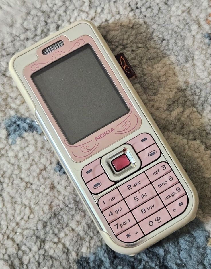 a pink cell phone sitting on top of a carpet