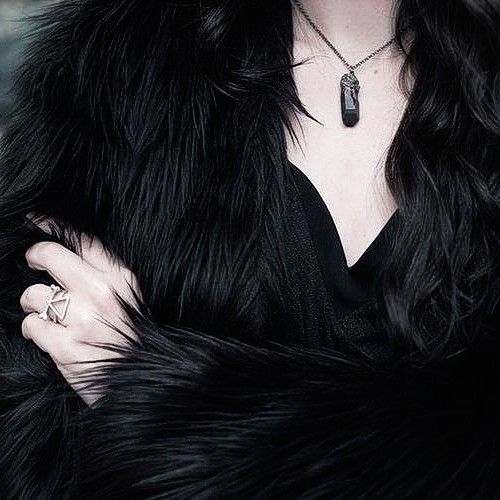 a woman wearing a black fur coat and ring