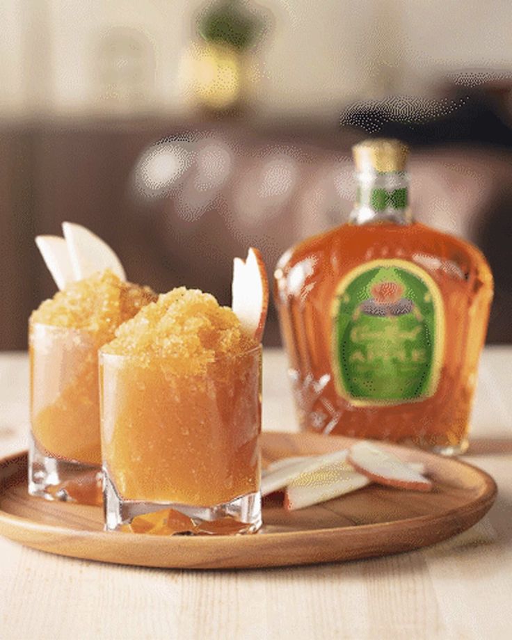 two cocktails on a wooden plate with a bottle in the background