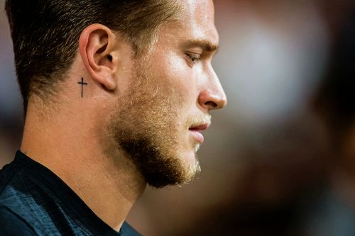 a man with a cross tattoo on his neck looking to the side while wearing a black shirt