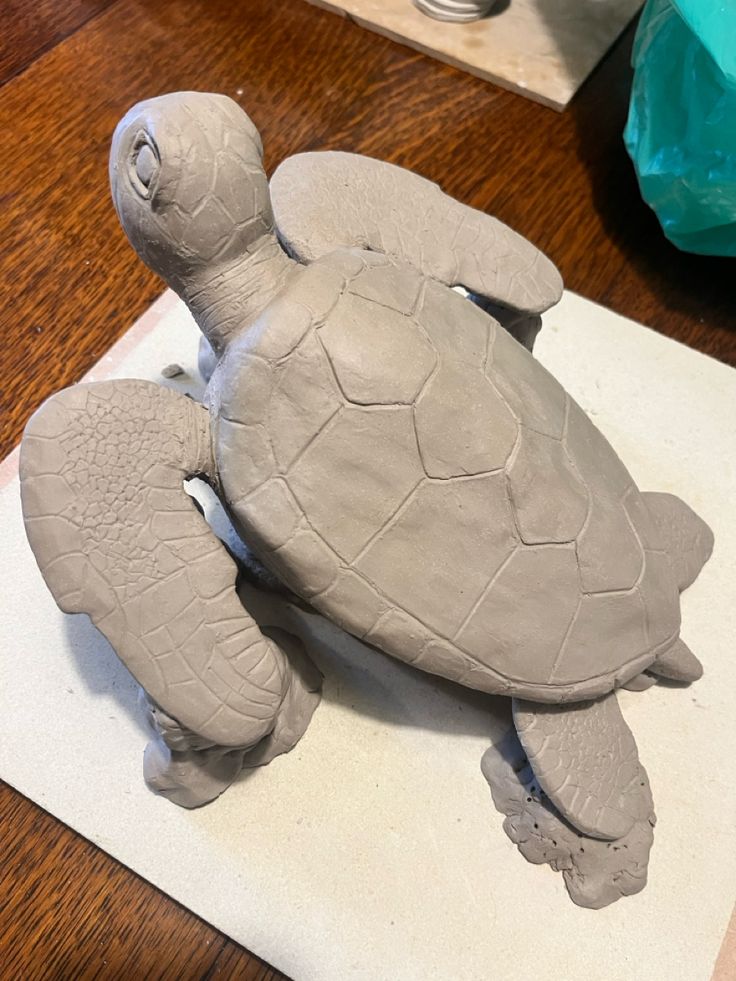 a clay turtle sitting on top of a wooden table